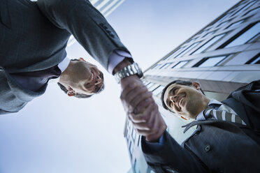 Corporate businessmen handshaking below building - CAIF06804