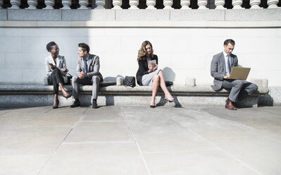 Corporate business people working on sunny bench outdoors - CAIF06805