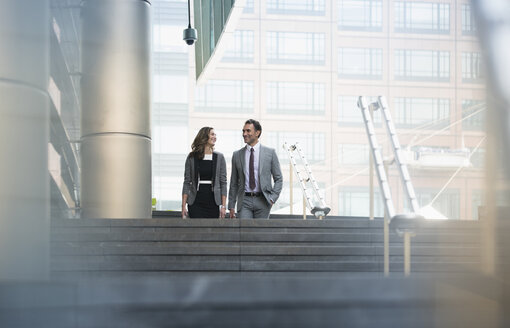 Geschäftsmann und Geschäftsfrau steigen eine Treppe im Freien hinunter - CAIF06811