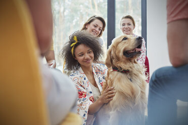 Woman petting dog in group therapy session - CAIF06843
