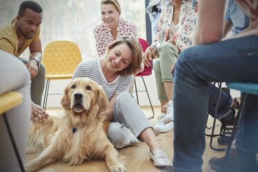 Woman petting dog in group therapy session - CAIF06853