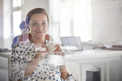 Portrait lächelnde Geschäftsfrau trinkt Kaffee im Büro - CAIF06874