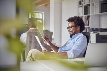 Businessman reading paperwork in office - CAIF06879