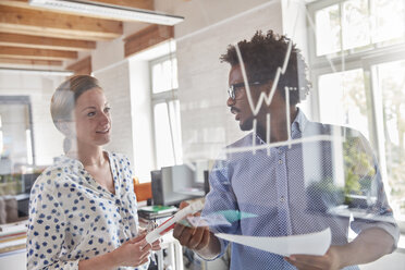 Geschäftsleute mit Papierkram Überprüfung Grafik auf Glas im Büro - CAIF06889