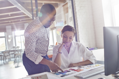 Design-Profis diskutieren im Büro über Farbmuster, lizenzfreies Stockfoto