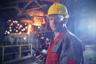 Porträt eines selbstbewussten, ernsten Stahlarbeiters mit Walkie-Talkie im Stahlwerk - CAIF06906