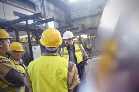 Aufsichtsperson und Stahlarbeiter bei einer Besprechung im Stahlwerk, lizenzfreies Stockfoto