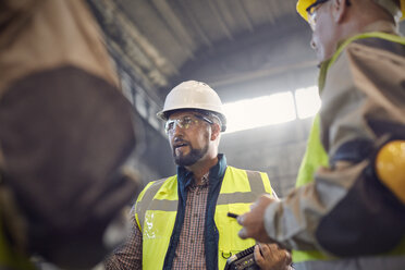 Aufsichtsperson im Gespräch mit Stahlarbeitern im Stahlwerk - CAIF06943