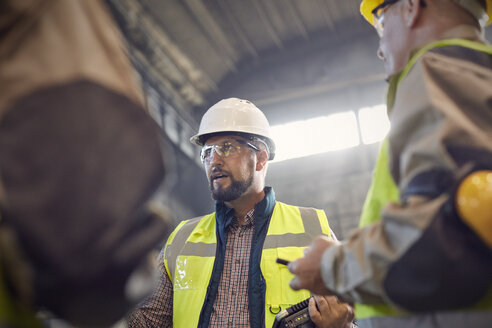 Supervisor talking to steelworkers in steel mill - CAIF06943