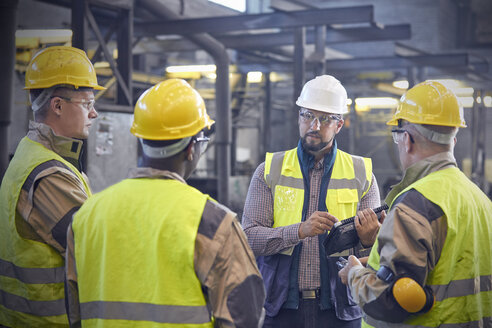 Supervisor talking with steelworkers in steel mill - CAIF06951