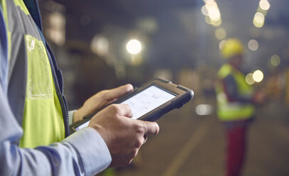 Nahaufnahme eines Stahlarbeiters, der ein digitales Tablet in einem Stahlwerk benutzt - CAIF06952