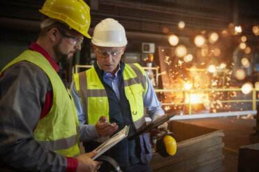 Supervisor and steelworker with clipboard talking in steel mill - CAIF06959