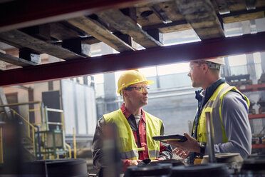 Steelworkers with digital tablet talking in steel mill - CAIF06961