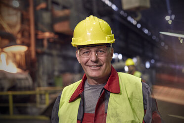 Porträt eines lächelnden, selbstbewussten Stahlarbeiters in einem Stahlwerk - CAIF06965