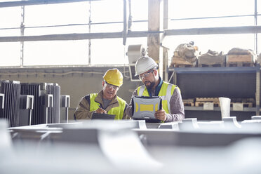 Steelworkers with laptop meeting in steel mill - CAIF06968