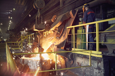 Stahlarbeiter auf einer Plattform über einem geschmolzenen Ofen in einem Stahlwerk - CAIF06976