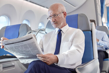 Älterer Geschäftsmann liest Zeitung im Flugzeug - CAIF06992