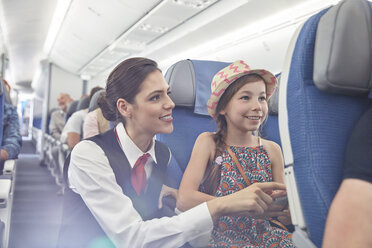 Female flight attendant helping girl on airplane - CAIF06997