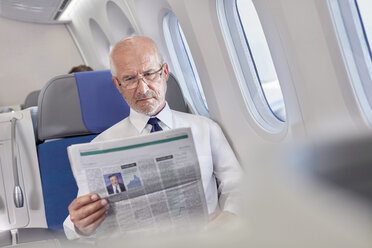 Geschäftsmann liest Zeitung im Flugzeug - CAIF07016