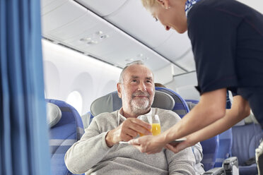 Flugbegleiter serviert Orangensaft an Mann im Flugzeug - CAIF07017