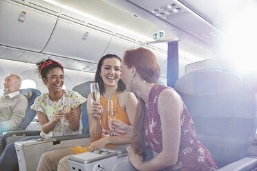 Junge Freundinnen trinken Champagner in der ersten Klasse eines Flugzeugs - CAIF07027