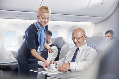 Flugbegleiter serviert Geschäftsmann in der ersten Klasse im Flugzeug Espresso, lizenzfreies Stockfoto