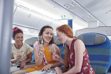 Junge Frauen Freunde lachen, trinken Champagner in der ersten Klasse im Flugzeug - CAIF07035