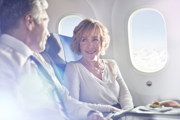 Geschäftsmann und Geschäftsfrau unterhalten sich in der ersten Klasse eines Flugzeugs - CAIF07042