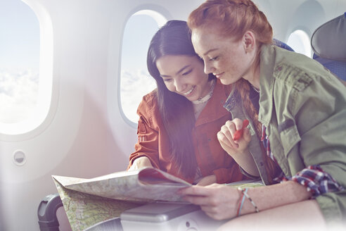 Junge Frauen, die sich im Flugzeug eine Karte ansehen - CAIF07045