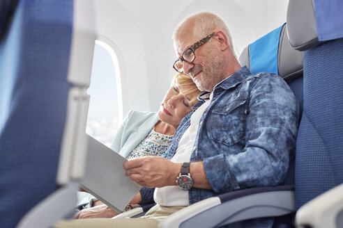 Zärtliches reifes Paar, das im Flugzeug schläft und liest - CAIF07047