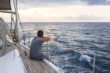 Indonesien, Insel Lombok, Mann sitzt an Deck eines Segelbootes - KNTF01081