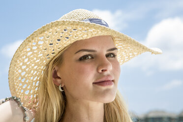Porträt einer jungen Frau, die am Strand einen Strohhut trägt - ZEF15165