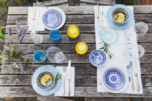 Garden table laid with colorful plates and bowls - GWF05465