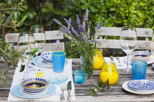 Gartentisch mit bunten Tellern und Schalen gedeckt - GWF05467