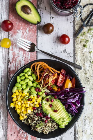 Quinoa veggie bowl of avocado, Edamame, tomatoes, corn, carrots, red cabbage and pomegranate seed stock photo