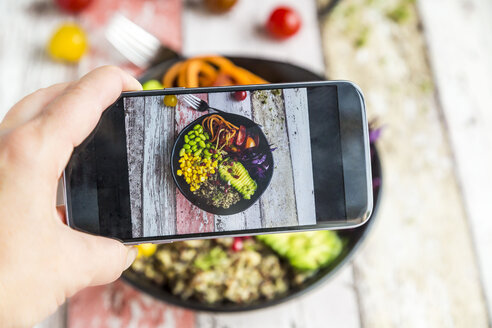 Girl taking photo of vegan Lunch bowl with cell phone, close-up - SARF03594