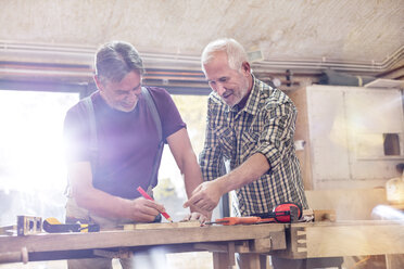 Männliche Schreiner beim Anzeichnen und Messen von Holz in der Werkstatt - CAIF07056
