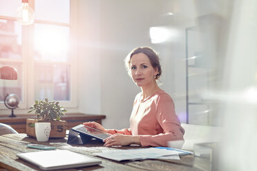 Porträt einer selbstbewussten Geschäftsfrau, die ein digitales Tablet am Schreibtisch im Büro benutzt - CAIF07083