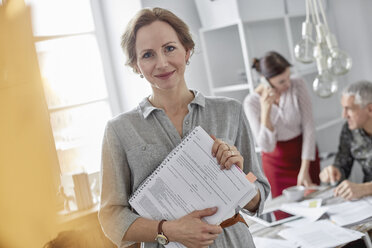 Portrait smiling businesswoman with paperwork in office meeting - CAIF07086