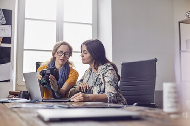 Female photographers with digital camera working at laptop in office - CAIF07103