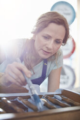 Focused female painter painting furniture with blue paint - CAIF07120