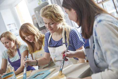 Künstlerinnen malen Bilderrahmen in einem Workshop der Kunstklasse, lizenzfreies Stockfoto