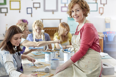 Porträt einer selbstbewussten, lächelnden Kunstlehrerin, die Schülern beim Malen in einem Kunstkurs-Workshop hilft - CAIF07148