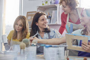 Lehrerin hilft Schülern beim Malen von Bilderrahmen in einem Kunstkurs-Workshop - CAIF07151