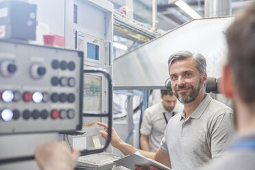 Portrait smiling male manager at machinery control panel in factory - CAIF07173