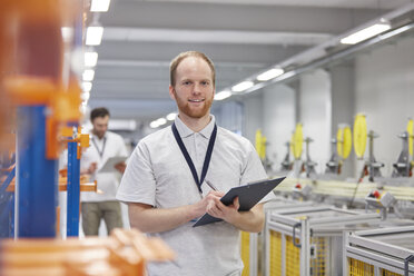 Portrait smiling, confident male supervisor with clipboard in fiber optics factory - CAIF07176