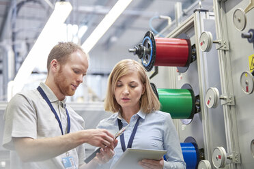 Männliche und weibliche Arbeiter mit digitalem Tablet, die ein Teil in einer Glasfaserfabrik untersuchen - CAIF07183