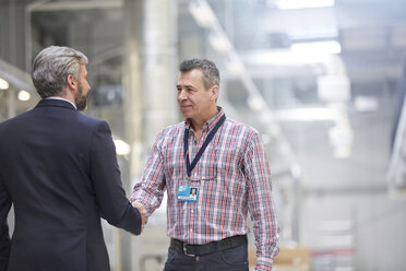 Businessman and supervisor handshaking in factory - CAIF07211