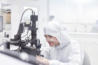 Ingenieurin in einem sauberen Anzug bei der Arbeit mit Geräten in einem Forschungs- und Testlabor für Glasfasertechnik - CAIF07229