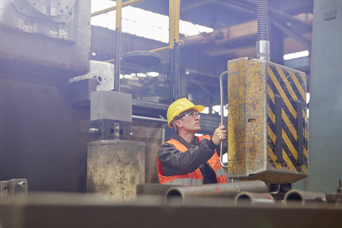 Männlicher Arbeiter, der Maschinen in einer Fabrik bedient, lizenzfreies Stockfoto